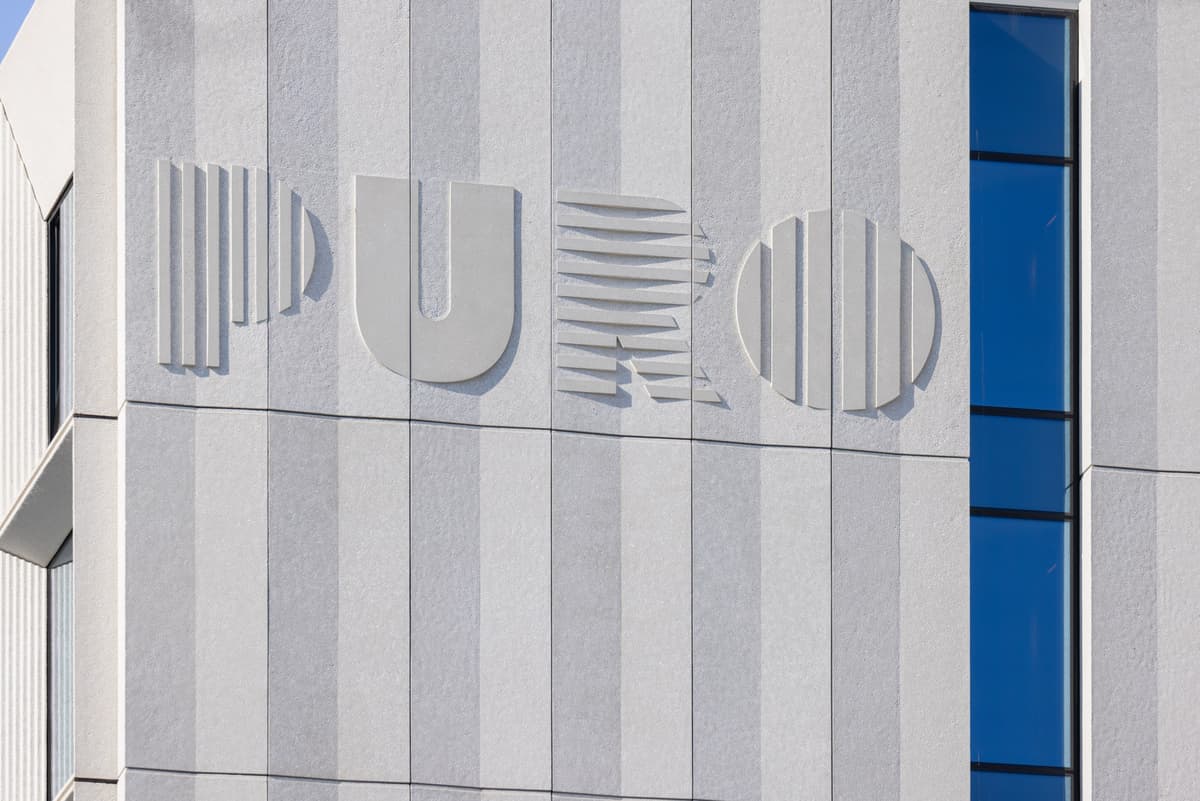 Logo hotelu PURO osadzone w prefabrykowanych panelach elewacyjnych – przykład integracji funkcji estetycznych i informacyjnych w betonie architektonicznym.